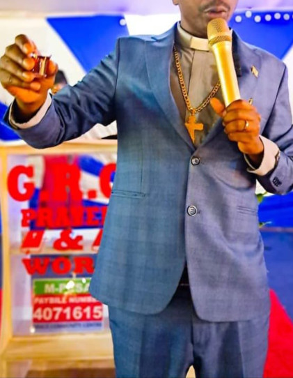 photo of a Reverend in his official attire, holding a small plastic communion cup