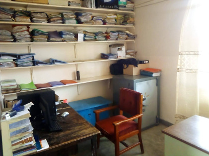 An office with some furniture including a table, a chair, and shelves with stacks of documents